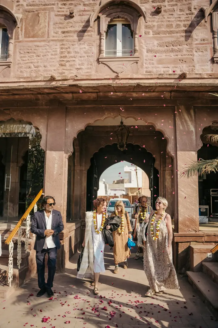 Guests arriving through the haveli gateway, petals on the path