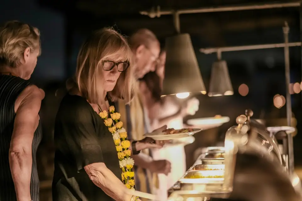 Guests at the dinner buffet under hanging lamps