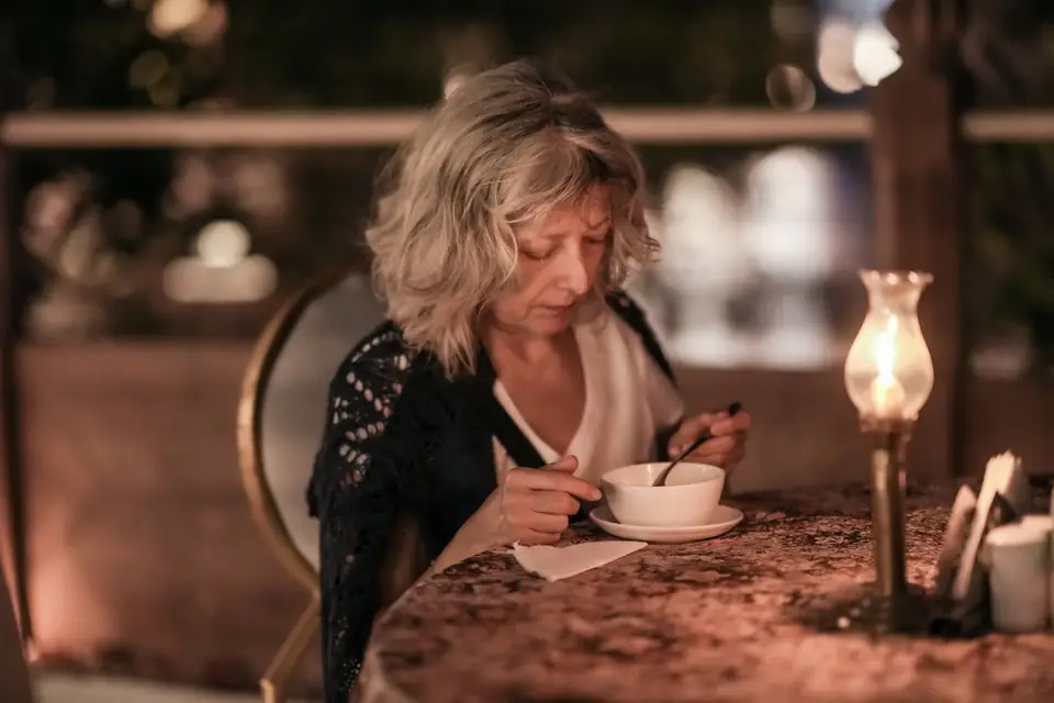 A guest at dinner beside an oil lamp