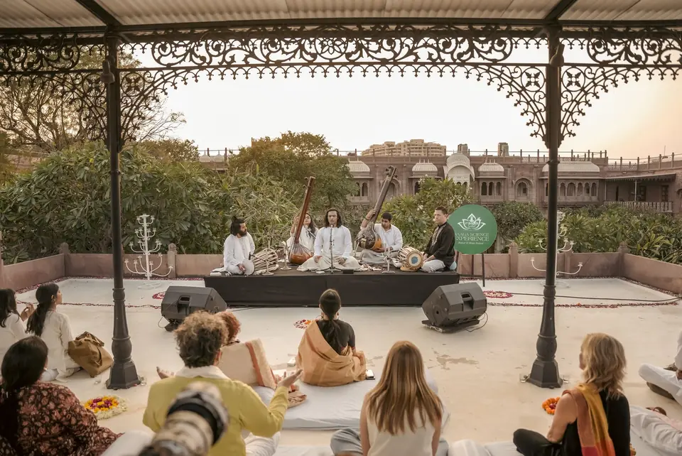 The rooftop pavilion at sunset, musicians on a low stage and guests on cushions