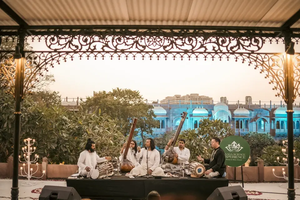 Musicians on the rooftop stage, the haveli lit blue behind them