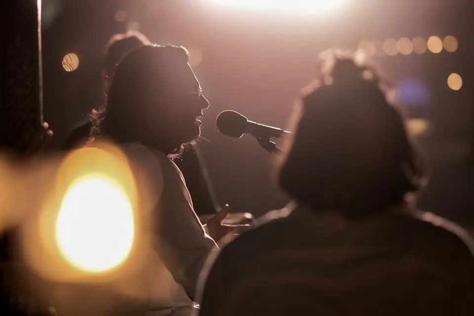 A vocalist at the microphone, lit by the last of the sun