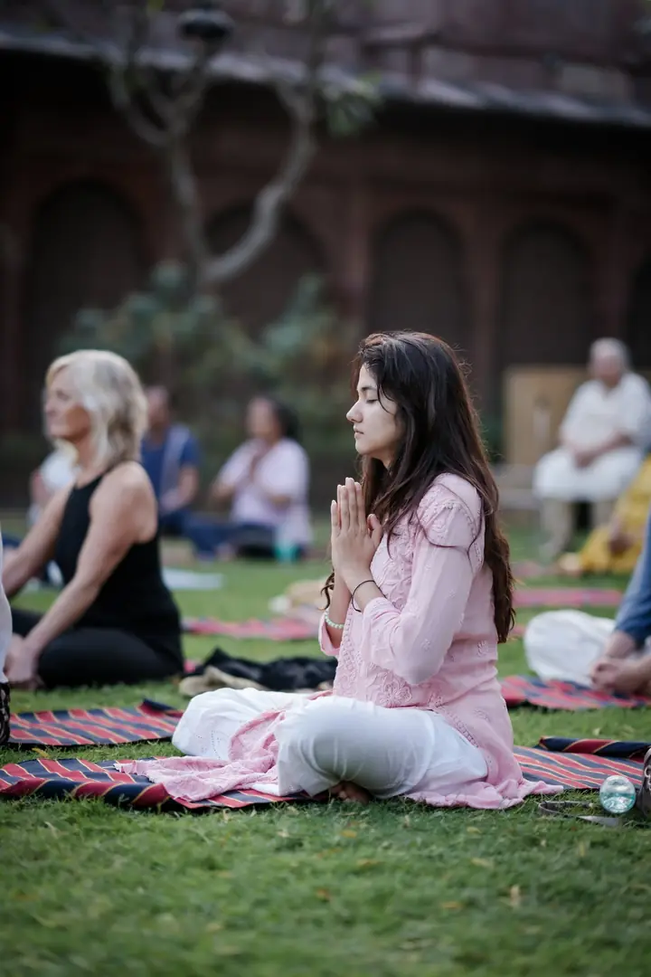 A guest seated on a mat, hands together at her chest