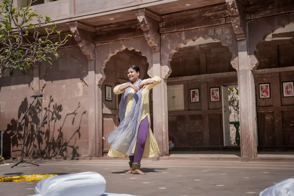A kathak dancer in the courtyard, arms raised mid-turn