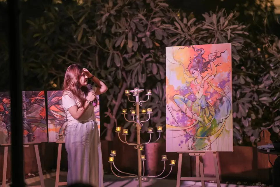 A singer beside a large painting, candles lit on stands