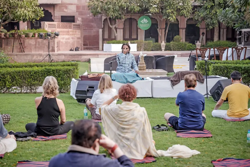 Guests in shawls facing the low stage on the lawn