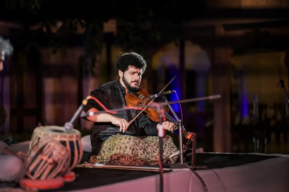 A violinist playing beside the tabla