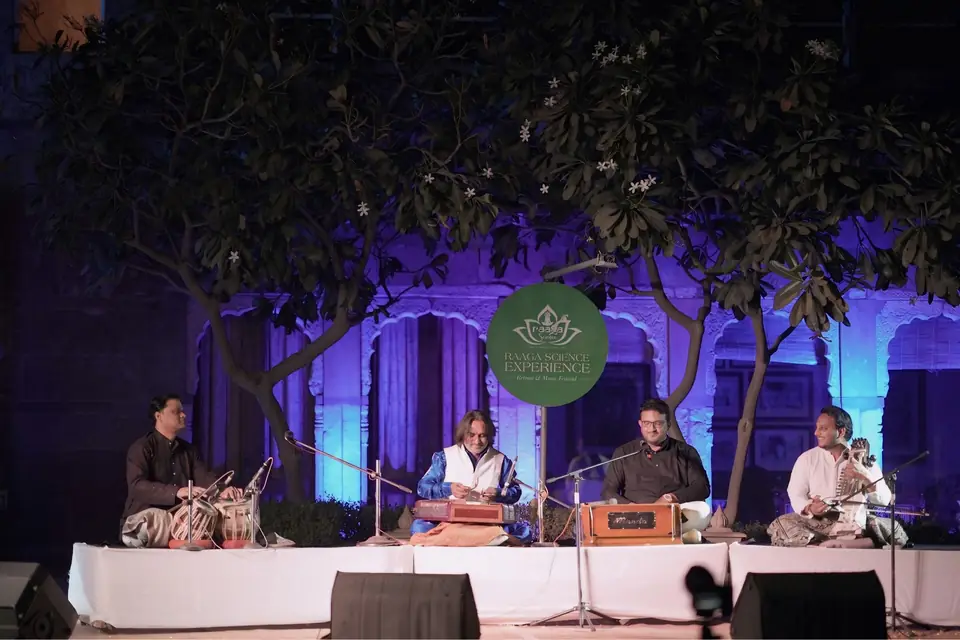 Santoor, tabla, harmonium and sarangi on the main stage, lit violet beneath the trees