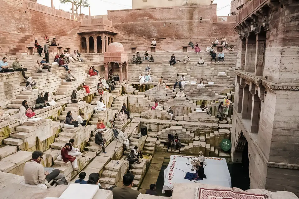 The stepwell’s stone terraces, guests seated on the steps