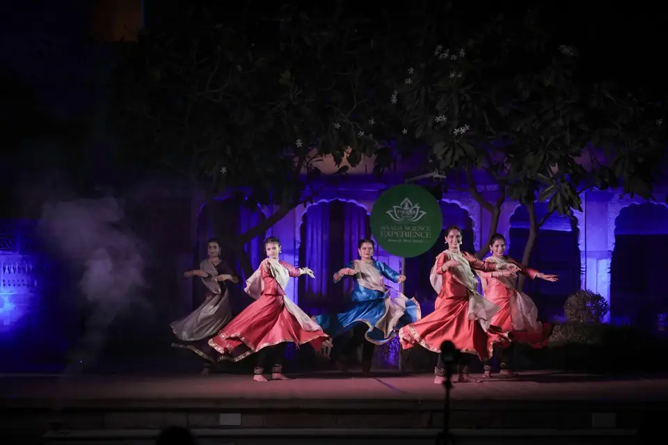 The kathak troupe mid-spin under violet light