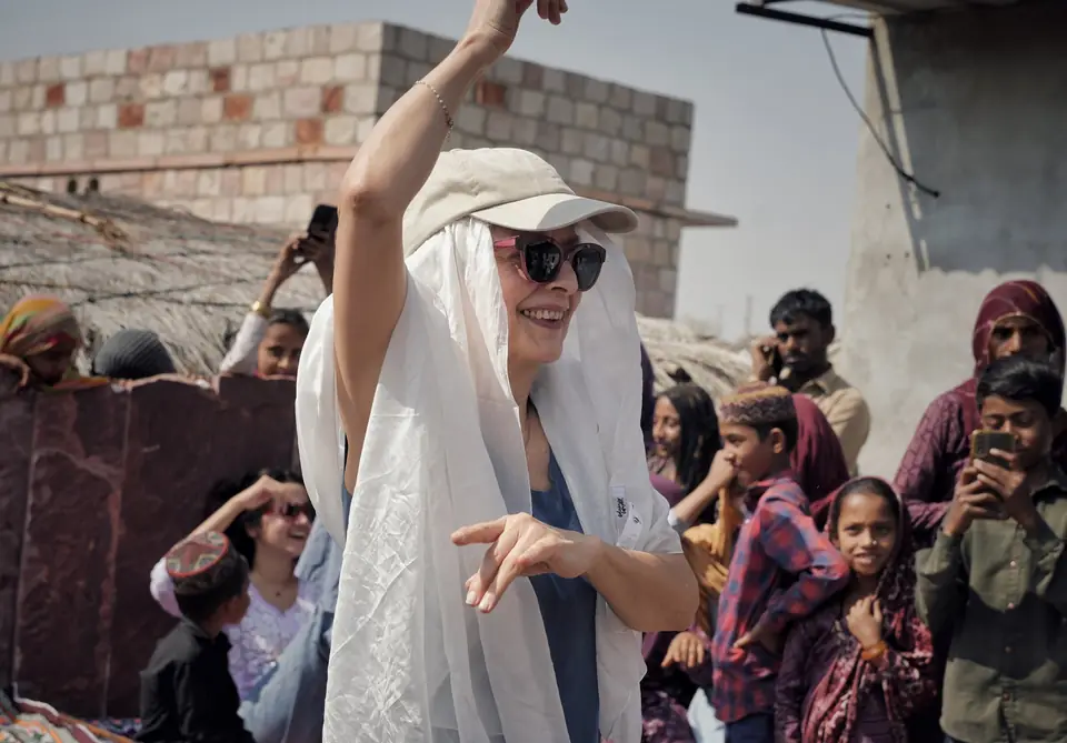 A guest in a white headscarf dancing, one arm raised