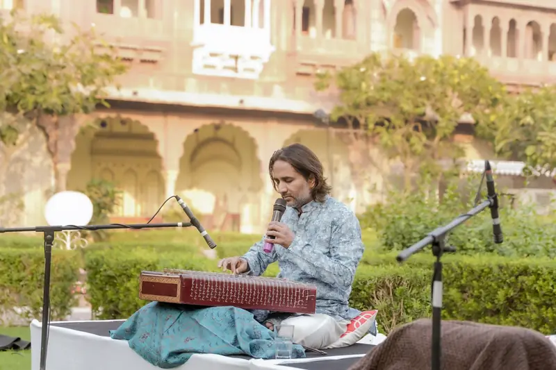 A santoor player performing in the haveli courtyard at golden hour